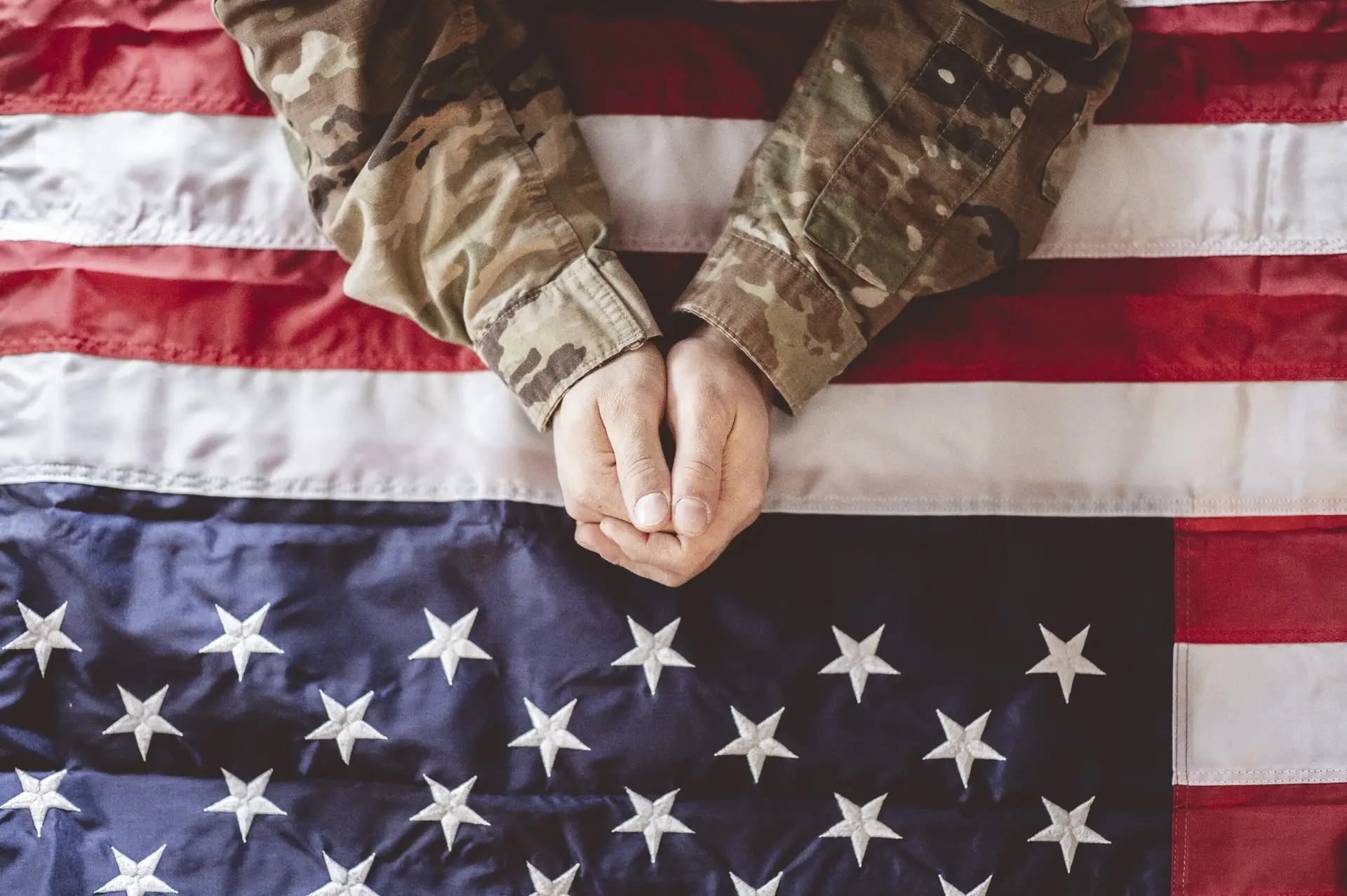 An American soldier mourning and praying with the American flag in front of him
